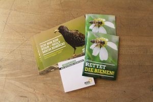 Im grünen Paket gegen Insektensterben sind Postkarten, Samentüten und Notizblöcke.