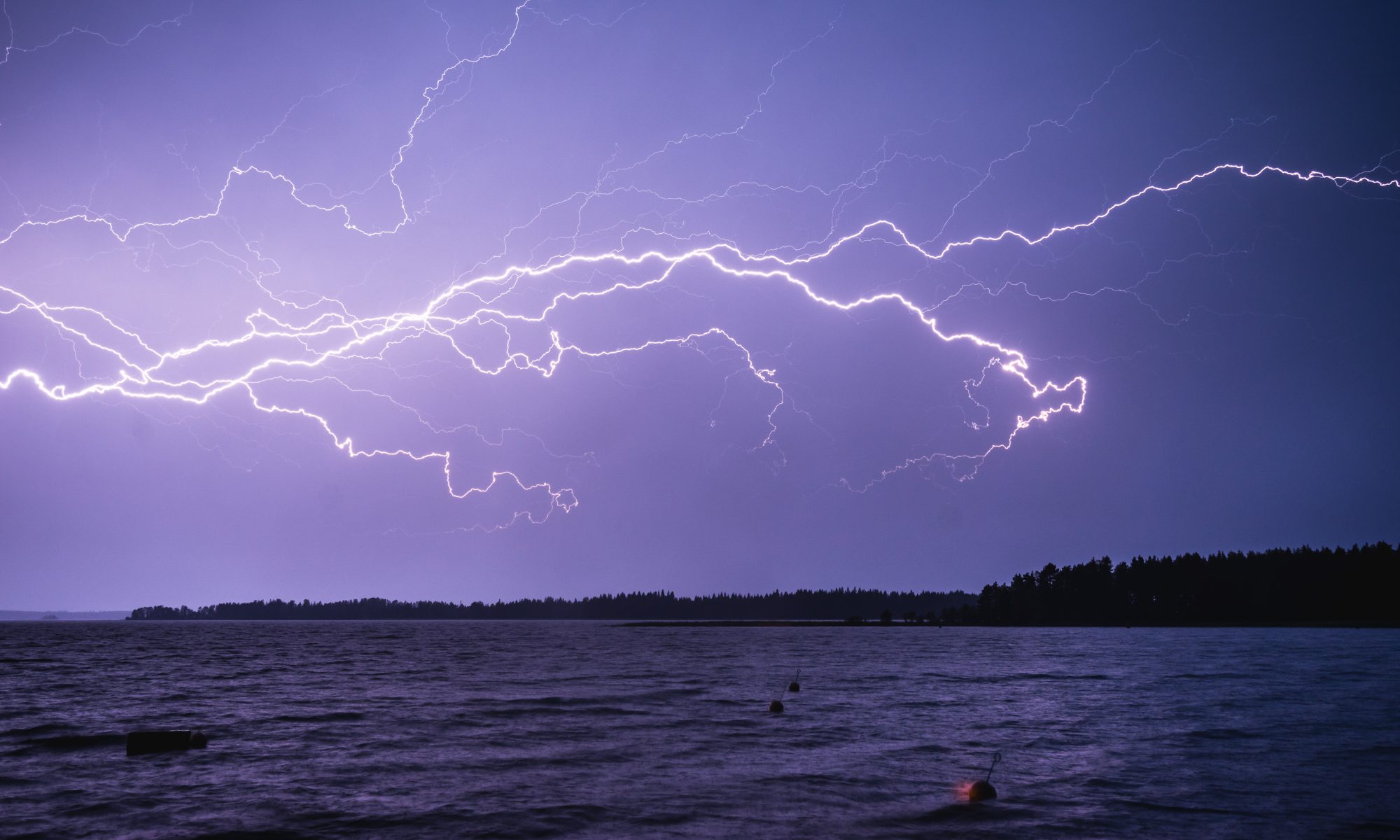 Blitzeinschlag über einem See. Unwetter und Extremwetterereignisse werden im Zuge der Klimakrise zunehmen.
