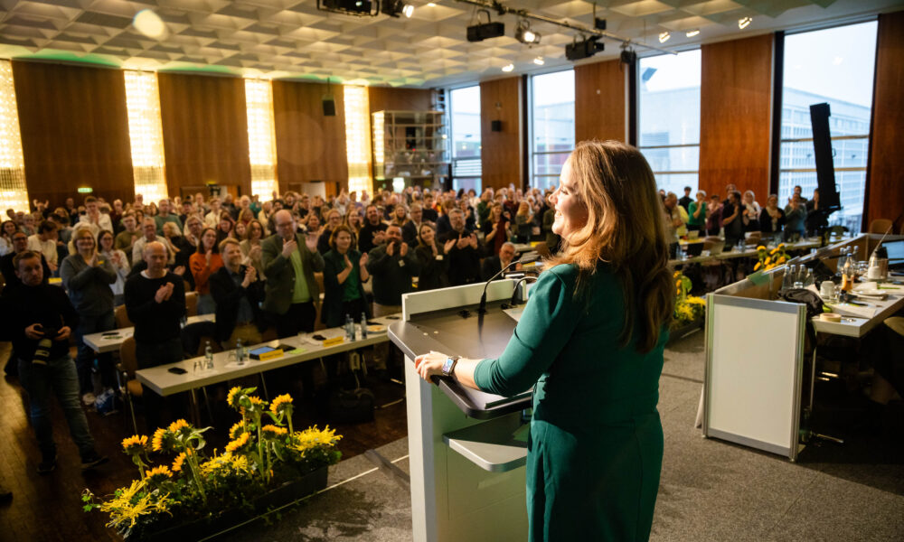 Ricarda Lang auf der LDK in Wolfsburg auf der Bühne. Das Publikum hält eine Standing Ovation.