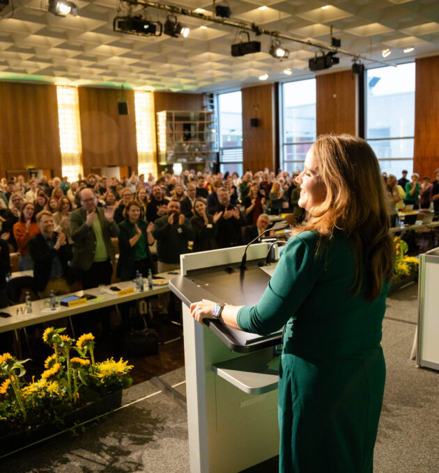 Ricarda Lang auf der LDK in Wolfsburg auf der Bühne. Das Publikum hält eine Standing Ovation.