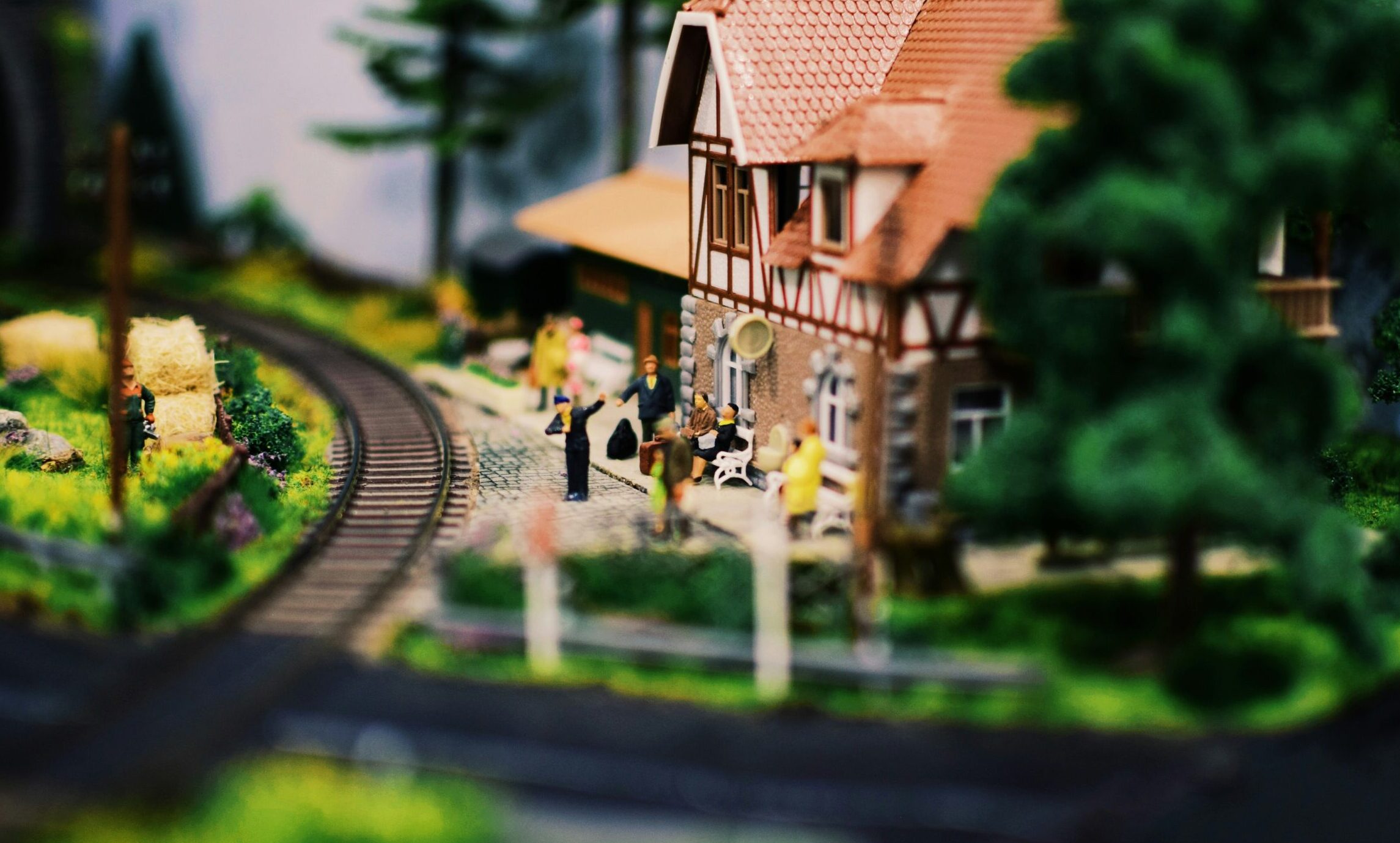 Bahnhof einer Modelleisenbahn. Kleine Figuren stehen am Bahnsteig und warten auf den nächsten Zug.