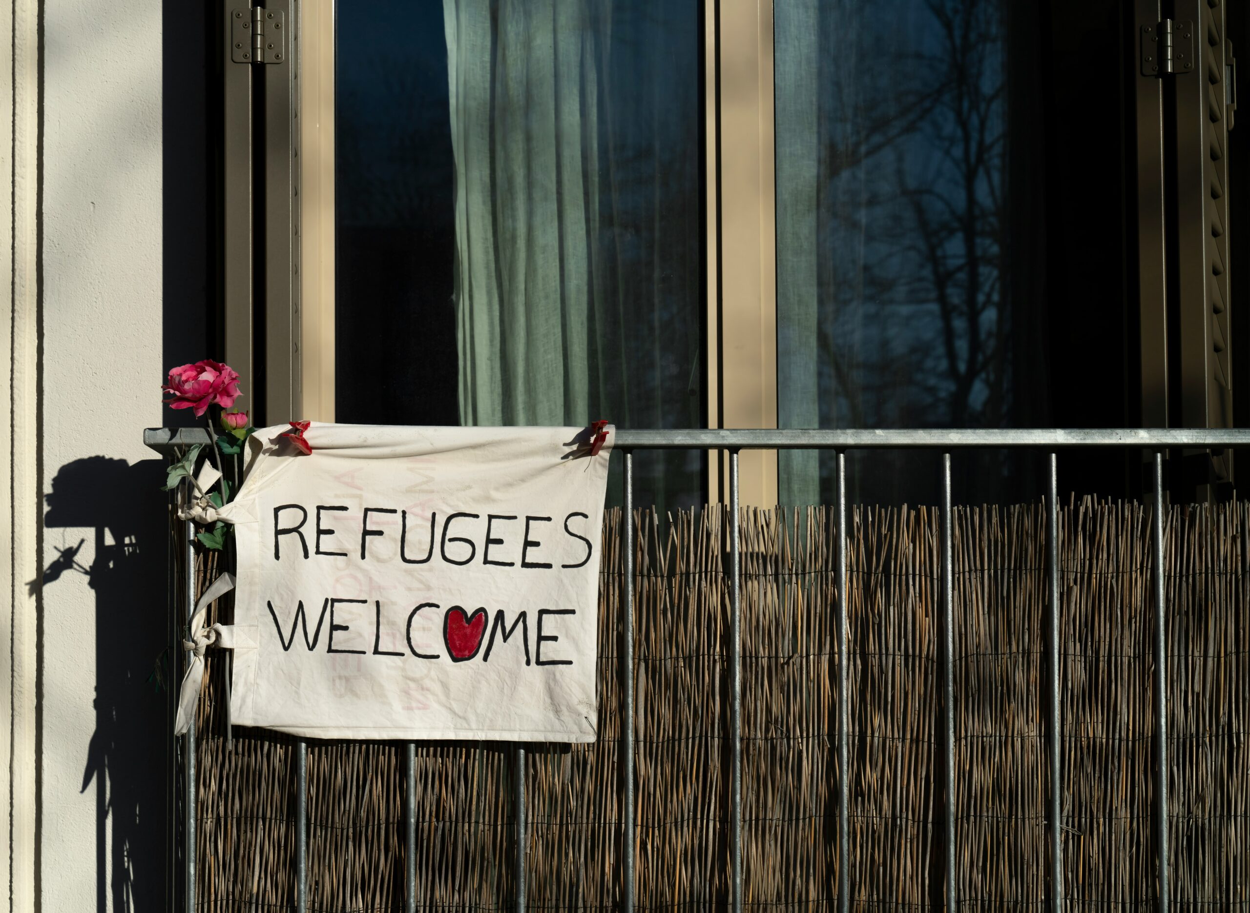 Ein Plakat mit der Aufschrift "Refugees Welcome" hängt an einem Balkon. Das bedeutet: "Geflüchtete willkommen"